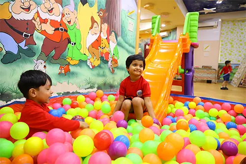 Preschool kids playing in a ball pit, having fun and laughing.